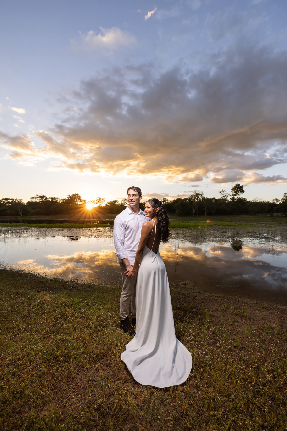 Indira e Ariel abraçados à beira do lago ao pôr do sol